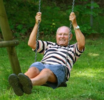 Ein älterer Mann sitz auf einer Schaukel